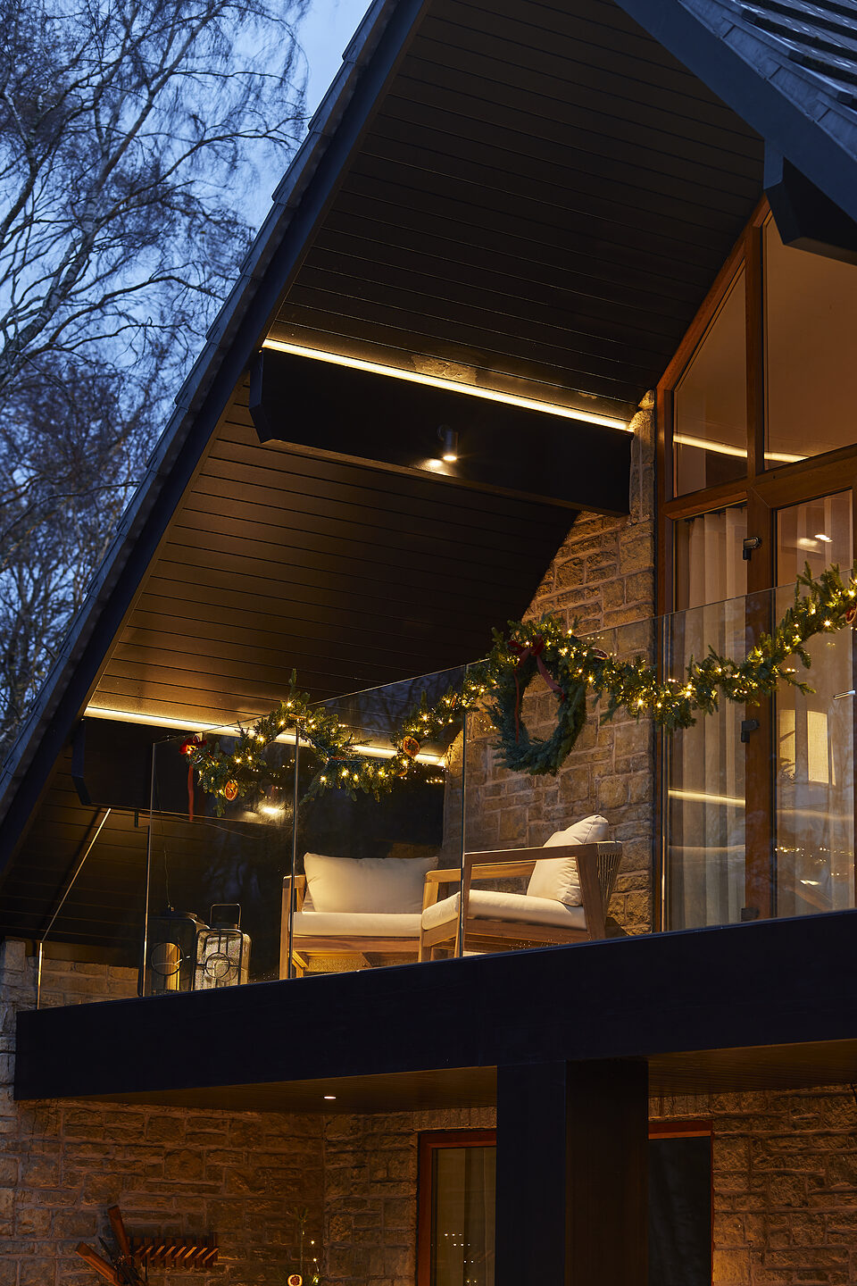 Balcony with evergreen garlands, wreaths, and warm festive lighting