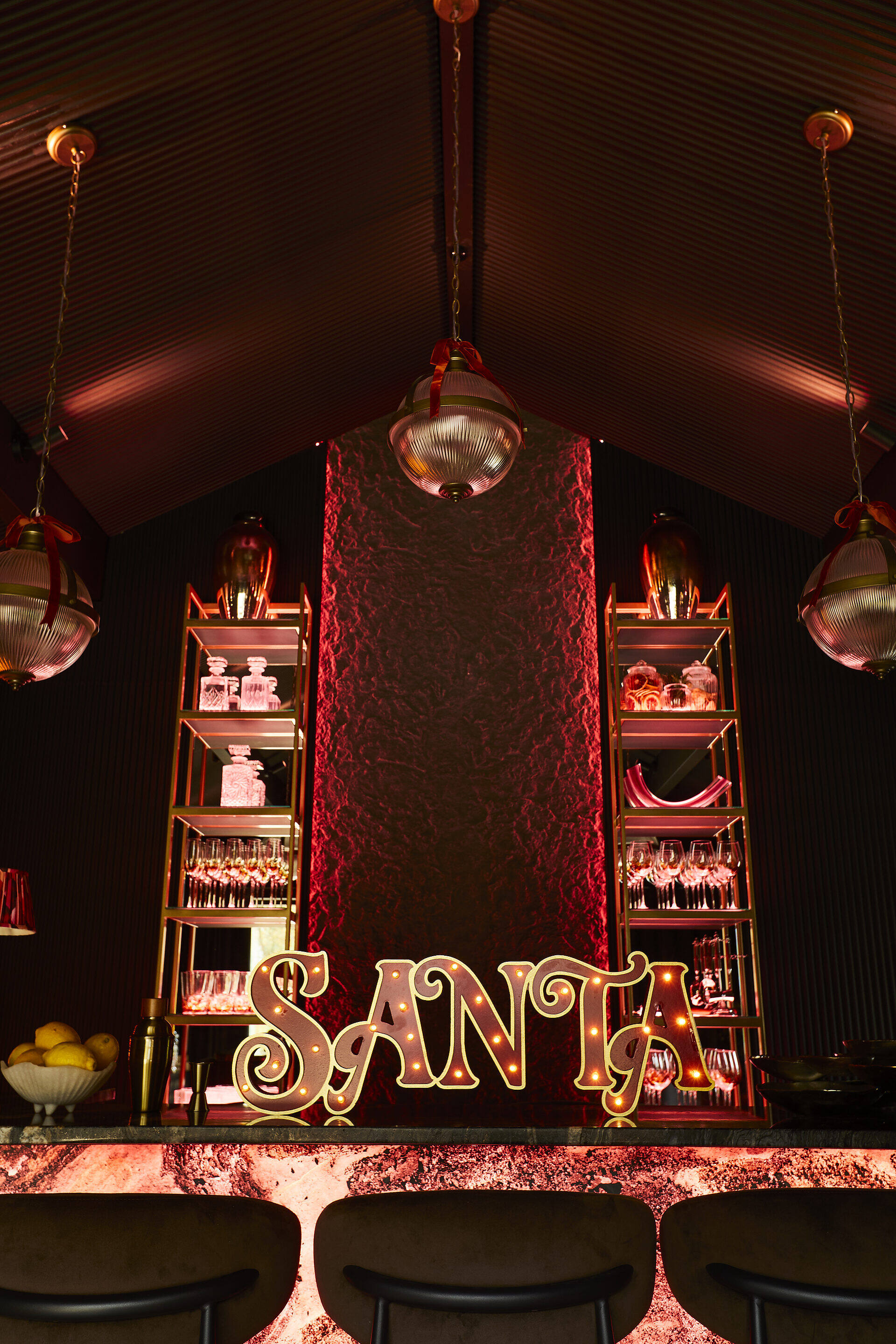 SANTA neon sign illuminating the private bar with crystal glassware