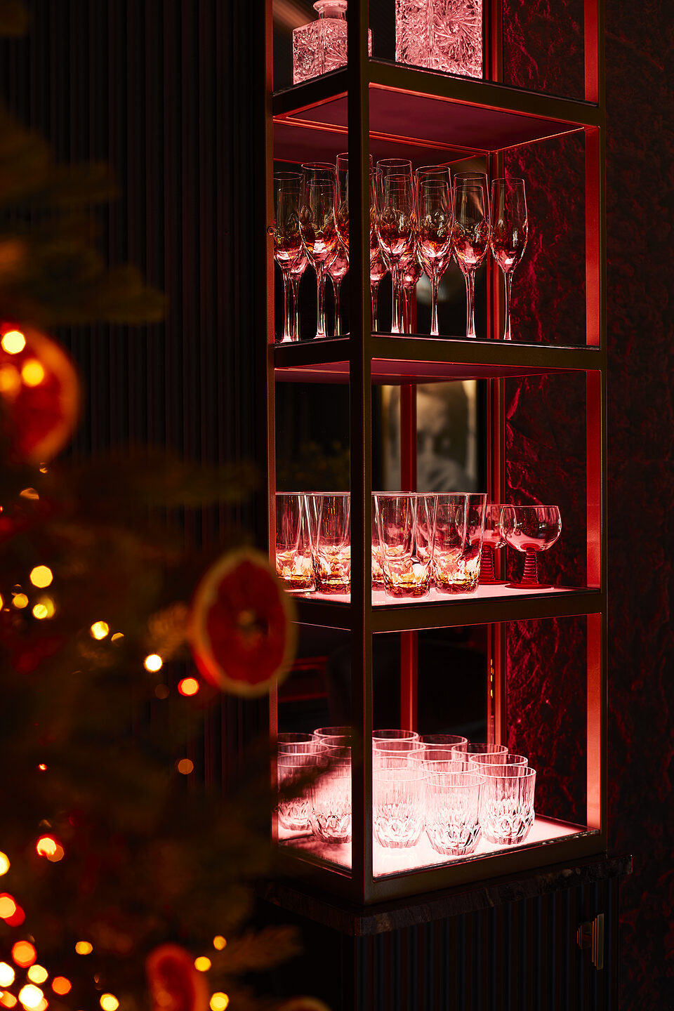 Crystal champagne flutes on illuminated bar shelves with tree