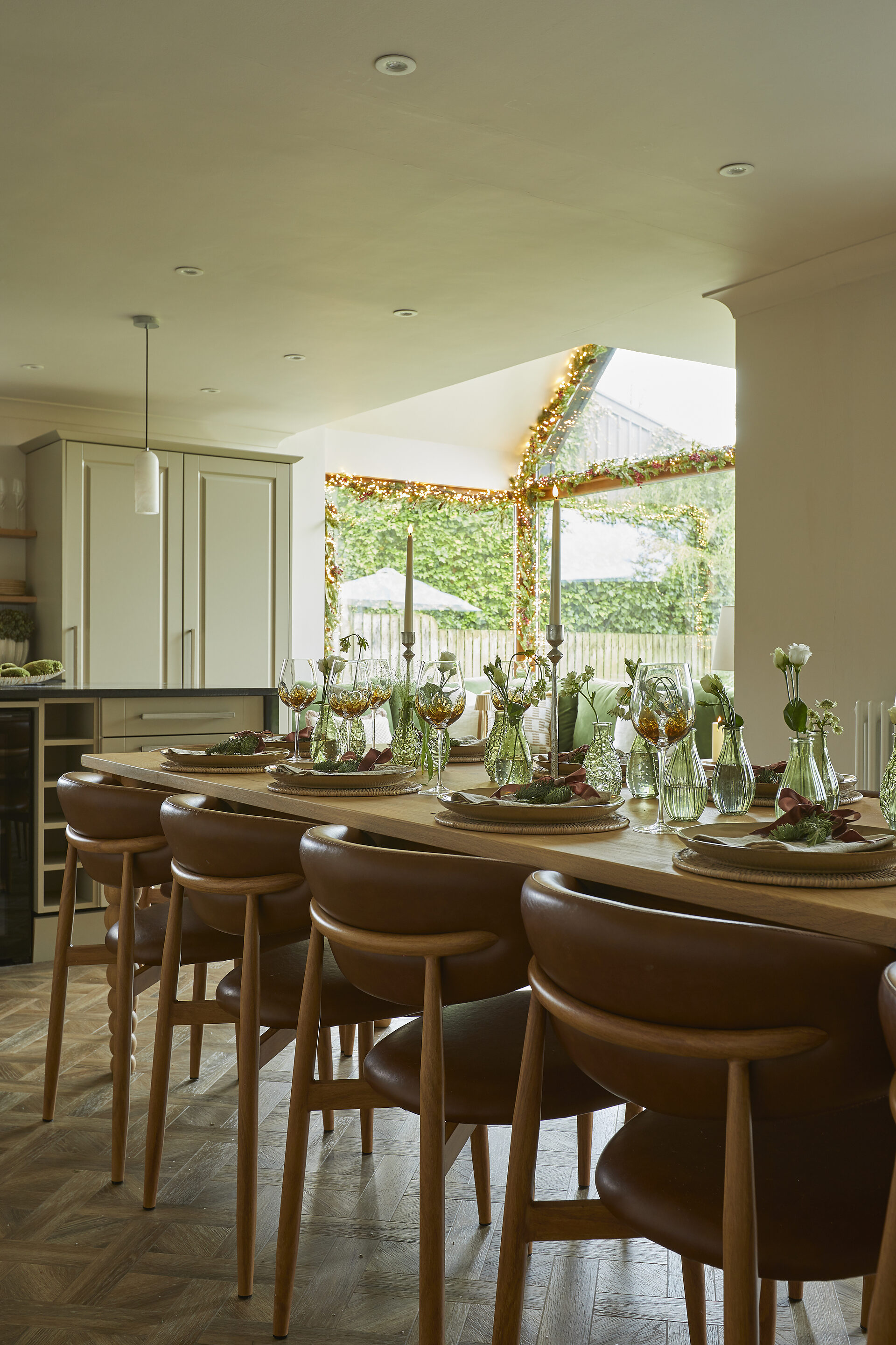 Leather dining chairs along the festive Christmas table with fairy lights on the window