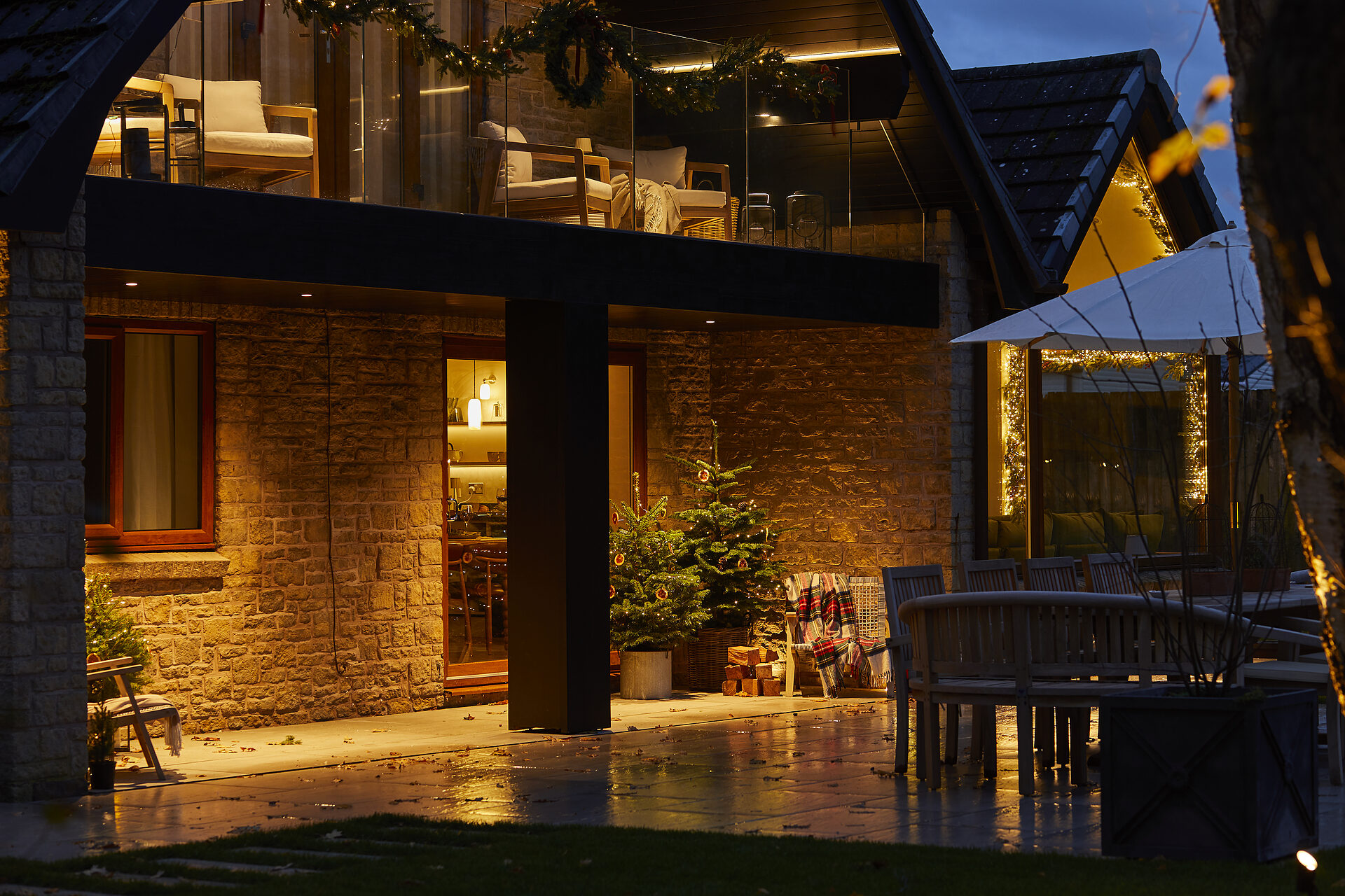 Warren House patio with Christmas tree, lit balcony, festive decorations against stone walls