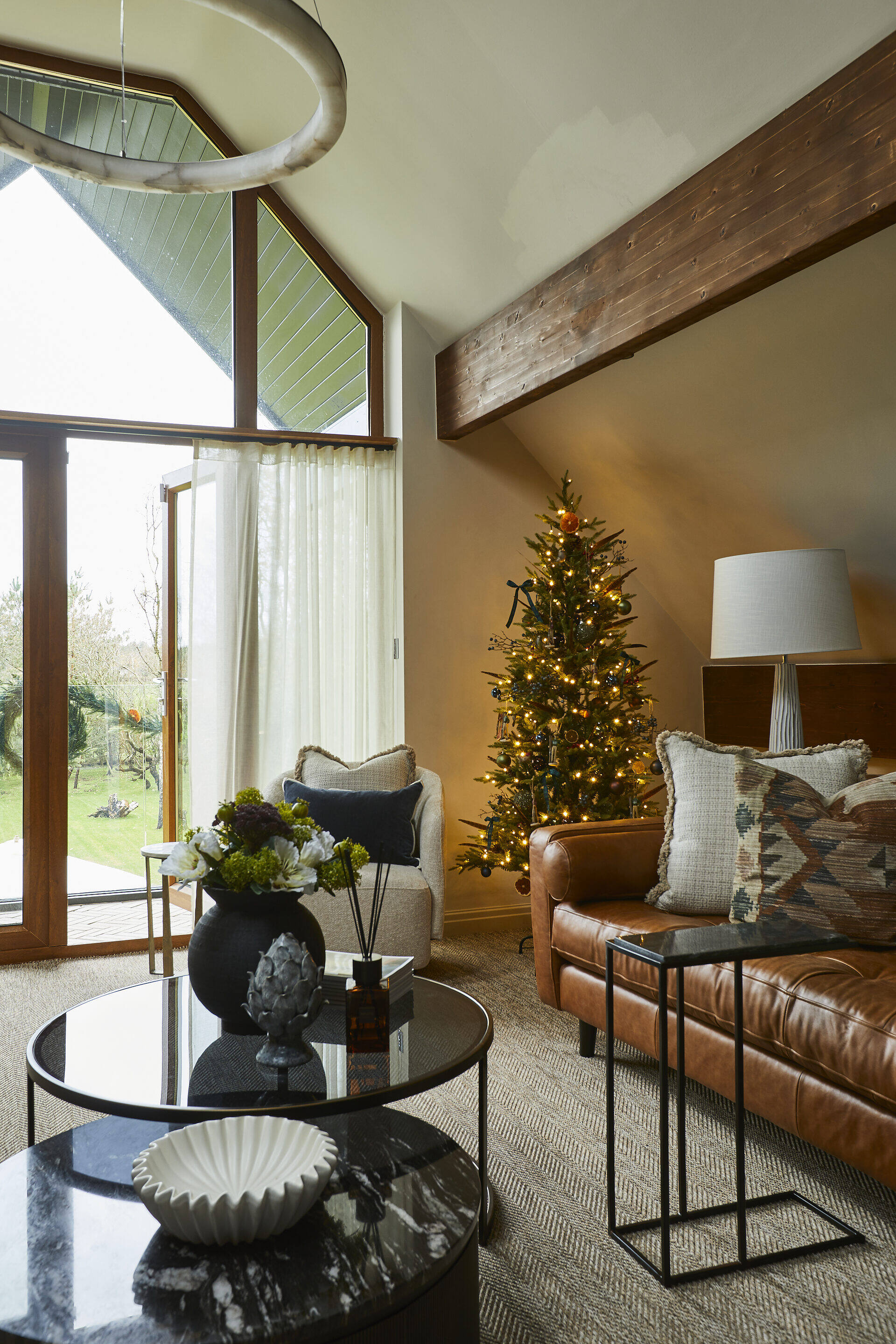 Living room with vaulted ceiling, exposed beams, leather sofas, Christmas tree