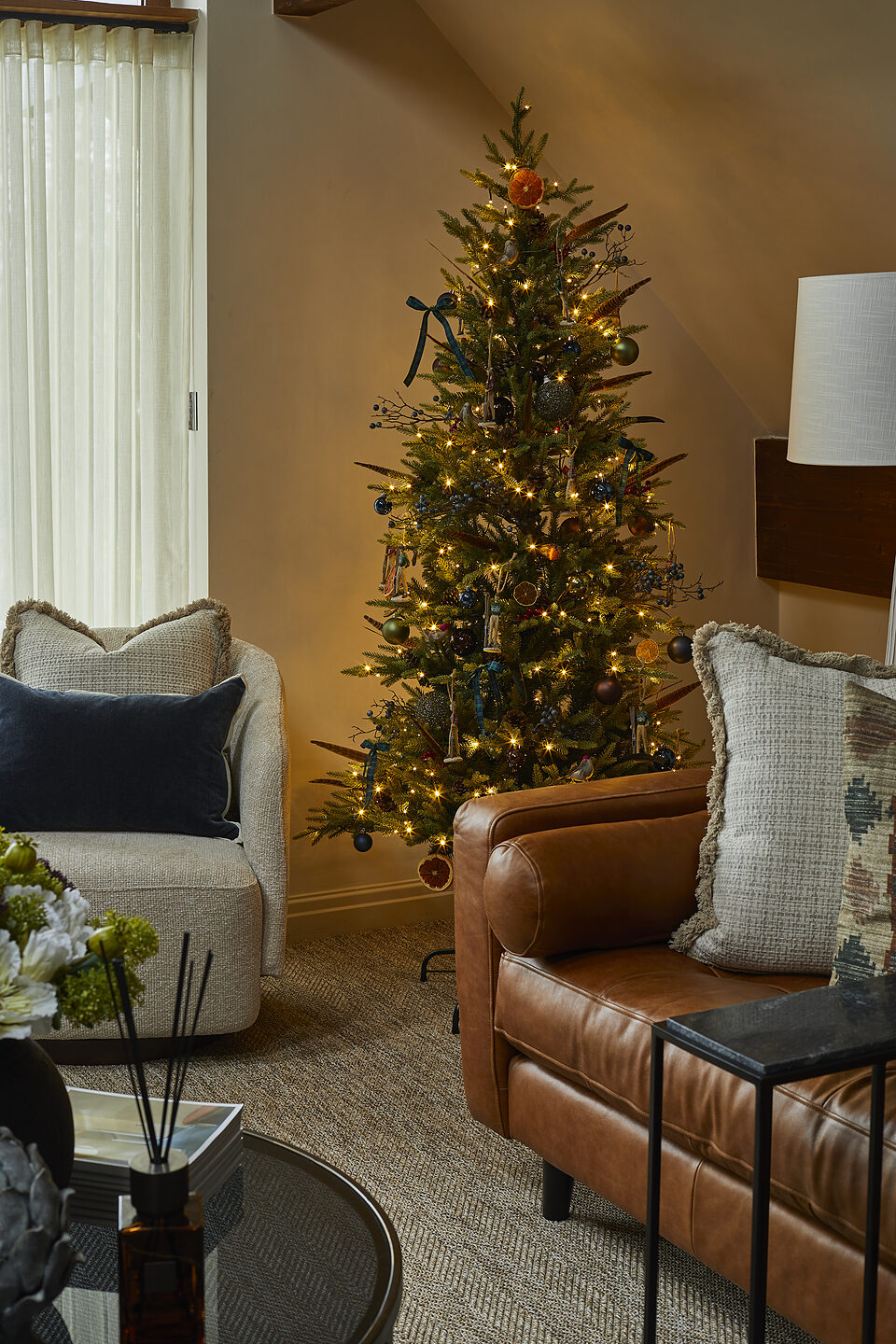 Decorated Christmas tree between cognac leather sofa and armchair