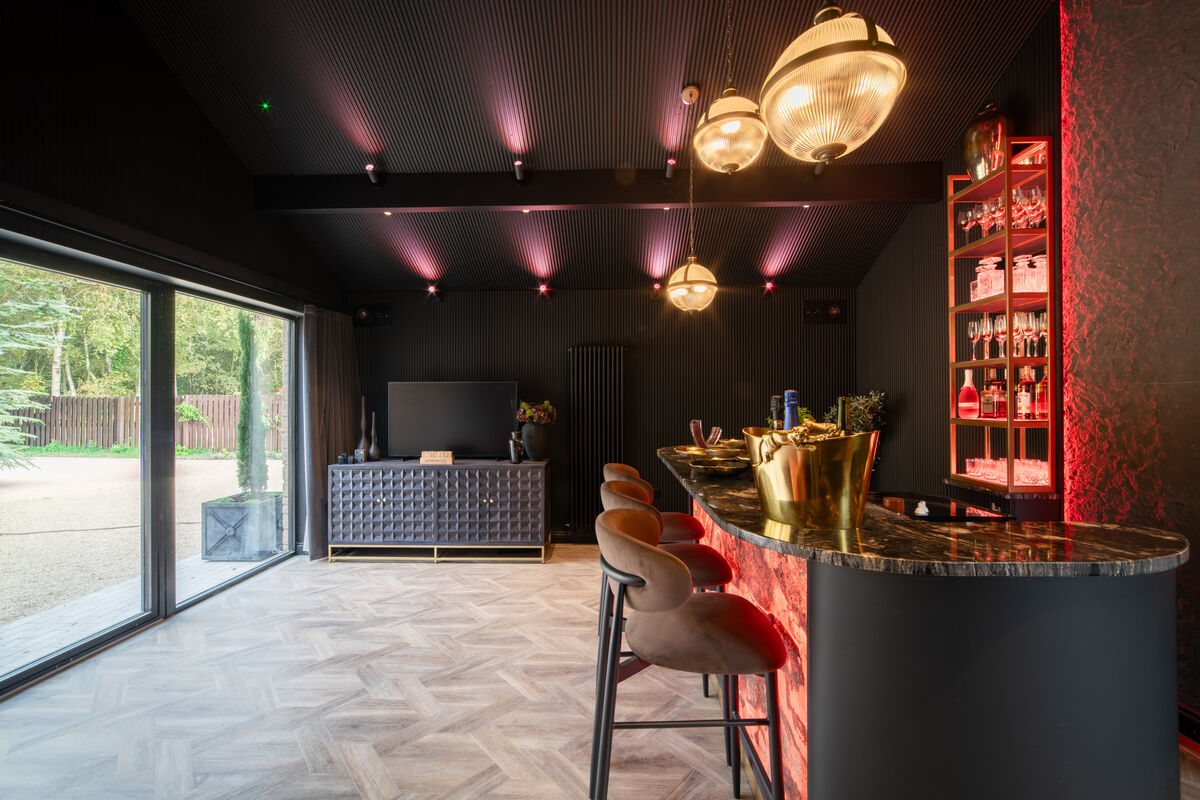 Private bar with red lighting, marble bar top, velvet stools and globe pendant lights