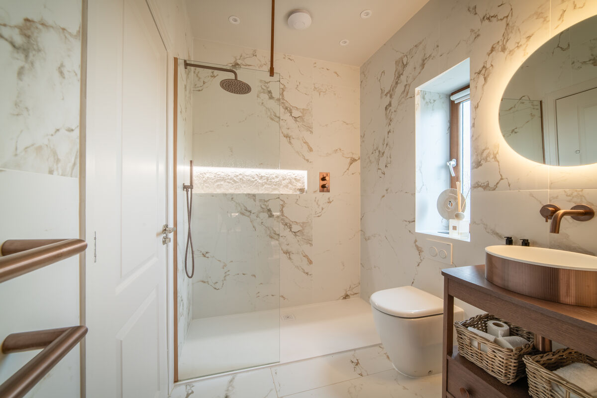 White marble en-suite bathroom with rain shower and copper fittings