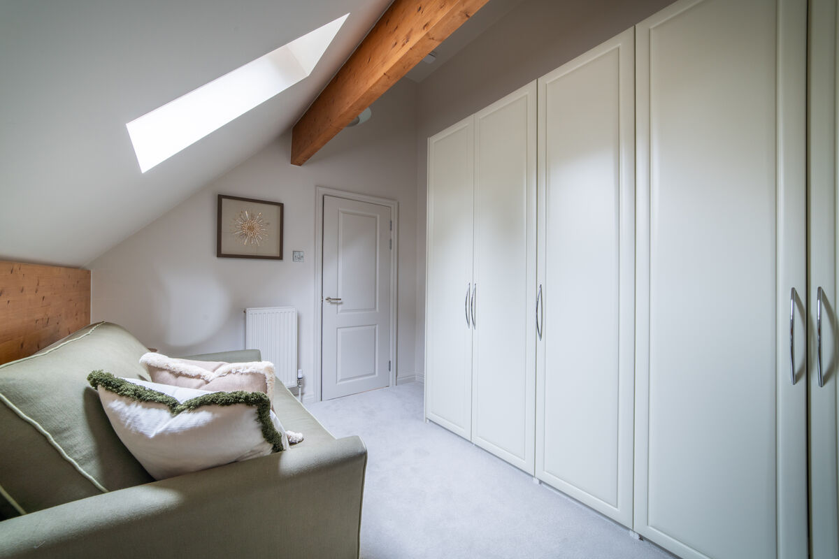 Built-in wardrobes, skylight and green sofa in bedroom four