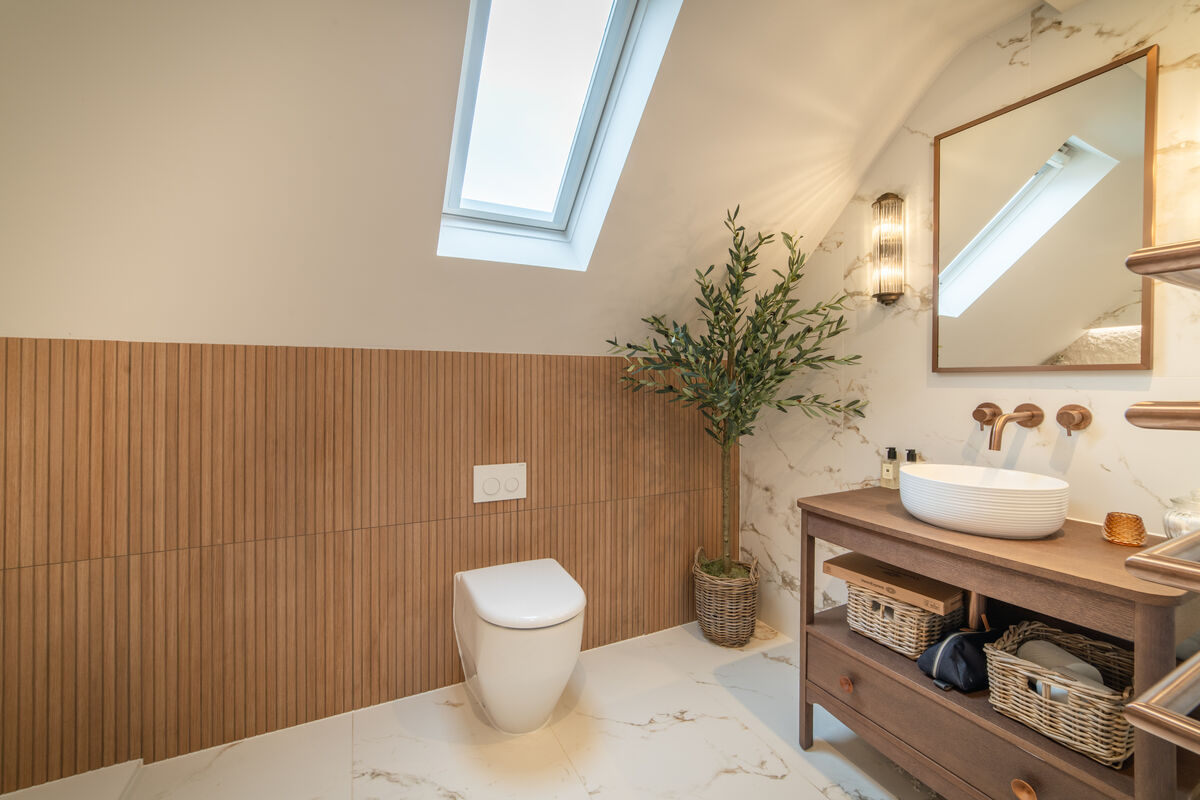 Wood-panelled bathroom with skylight, olive tree and copper fittings