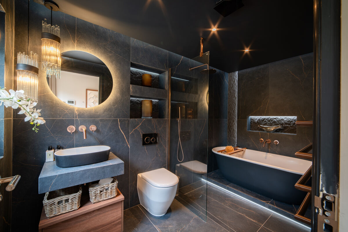 Dark marble en-suite with freestanding bath, walk-in shower and copper fittings