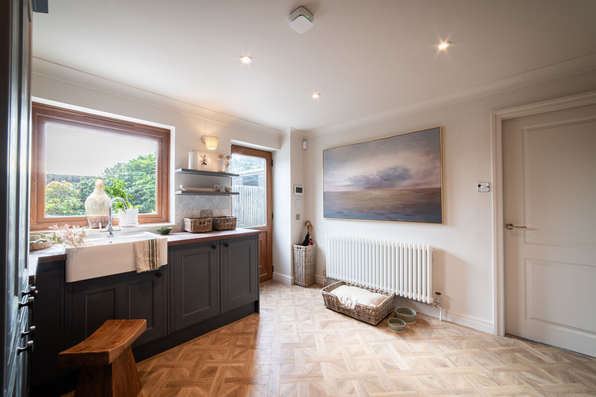 Utility area with Belfast sink, large window, landscape painting and dog bed