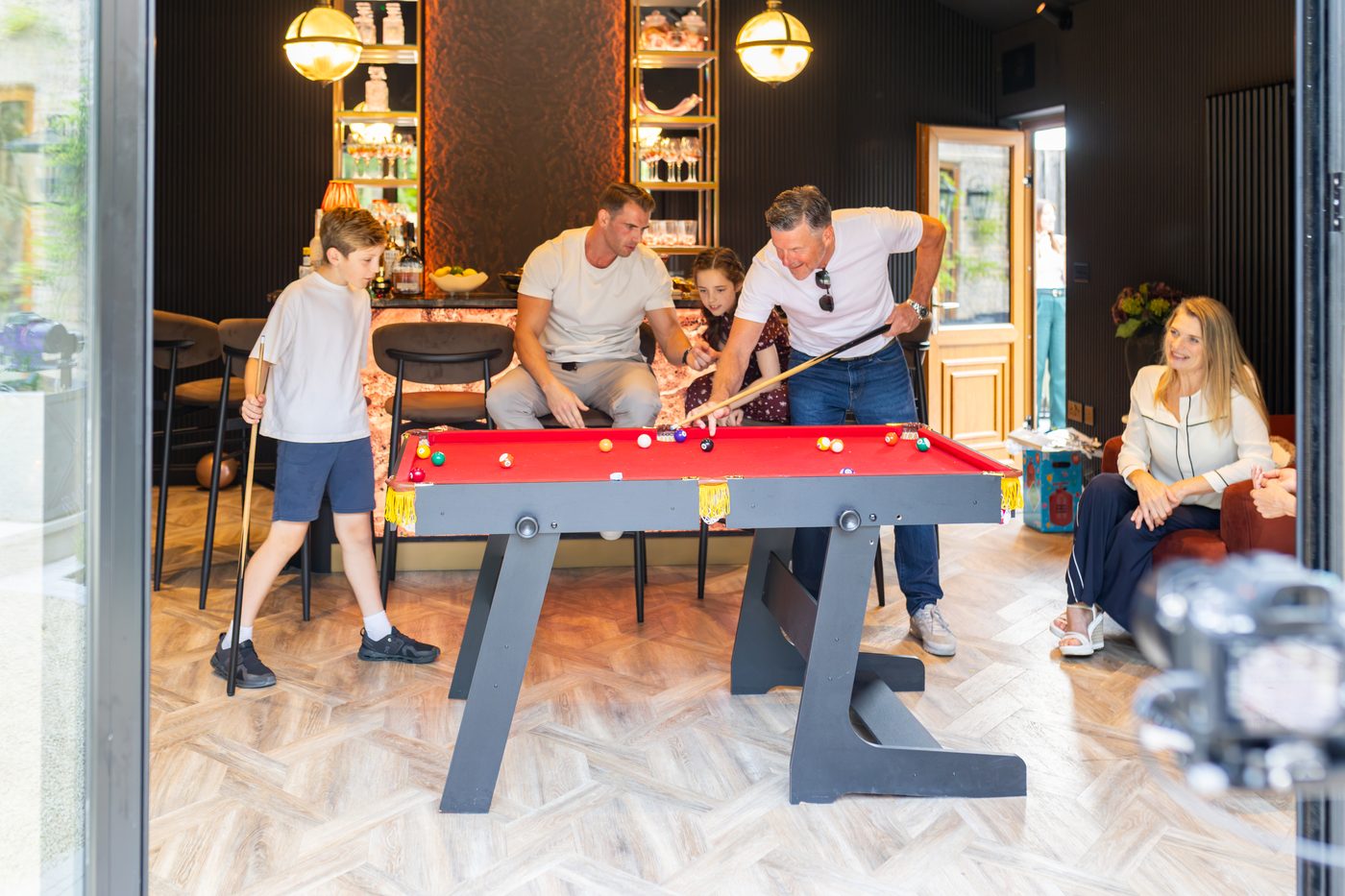 A family game on the red pool table beside the marble bar at Warren House