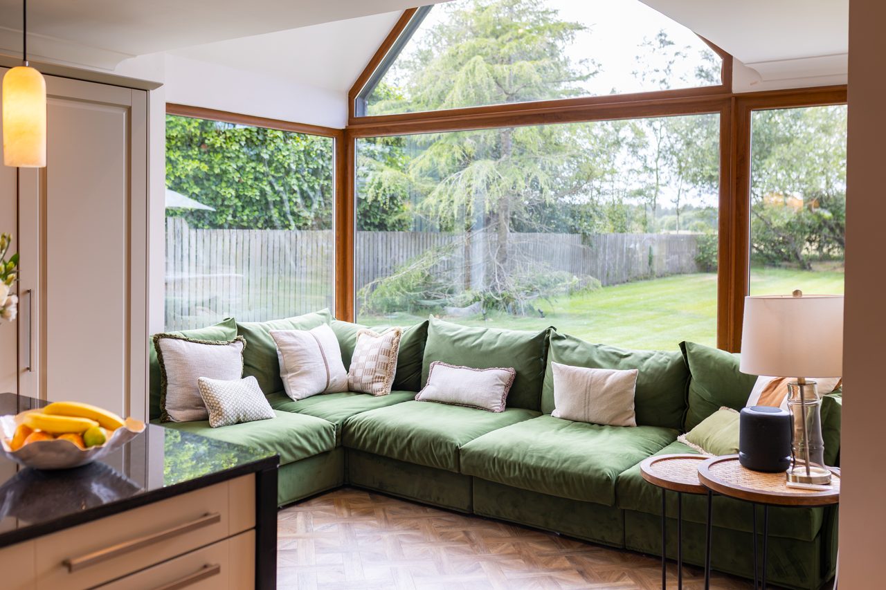 The green velvet sofa snug beside the Warren House kitchen