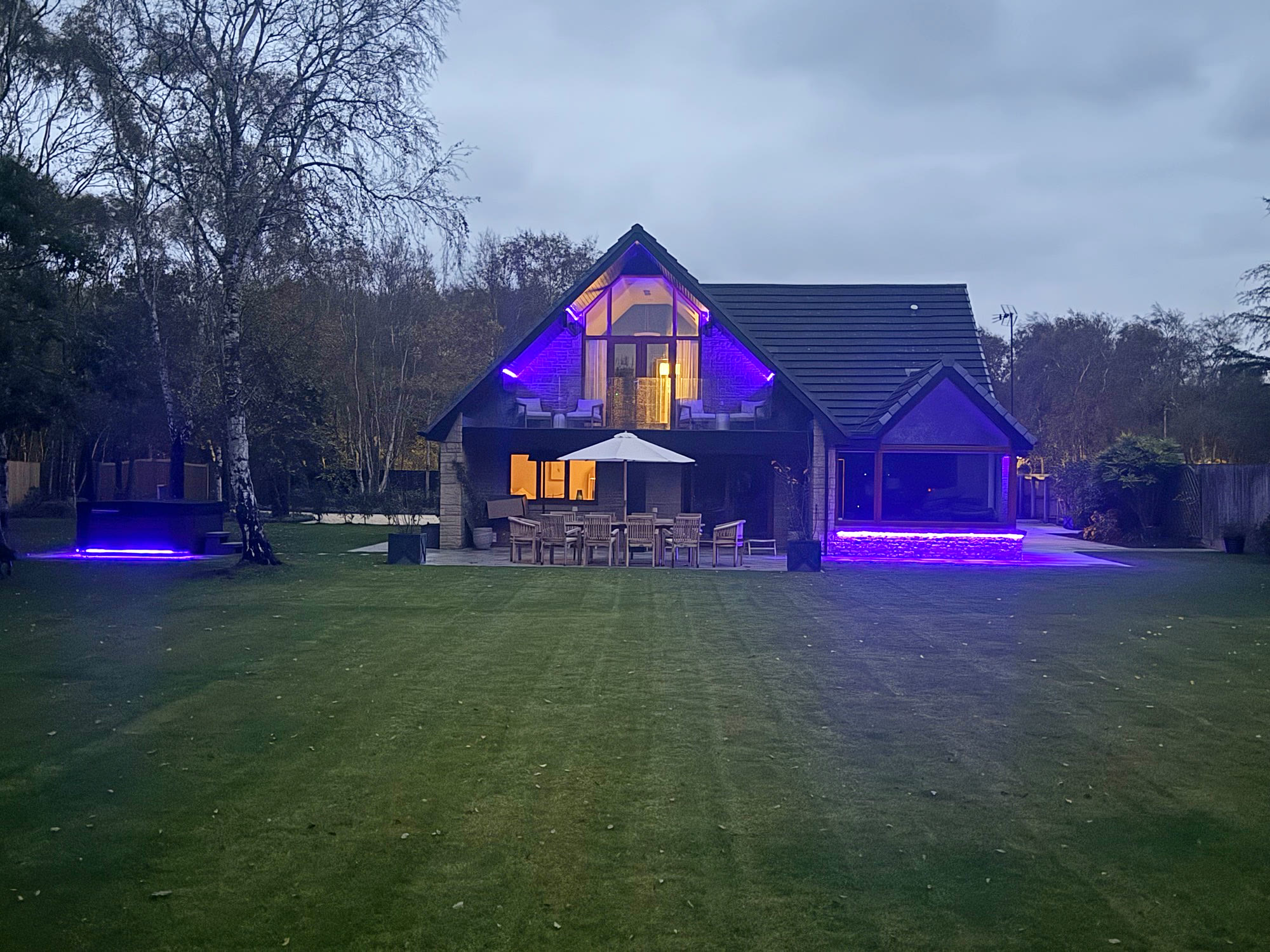 Warren House glowing in colour-changing light after dark