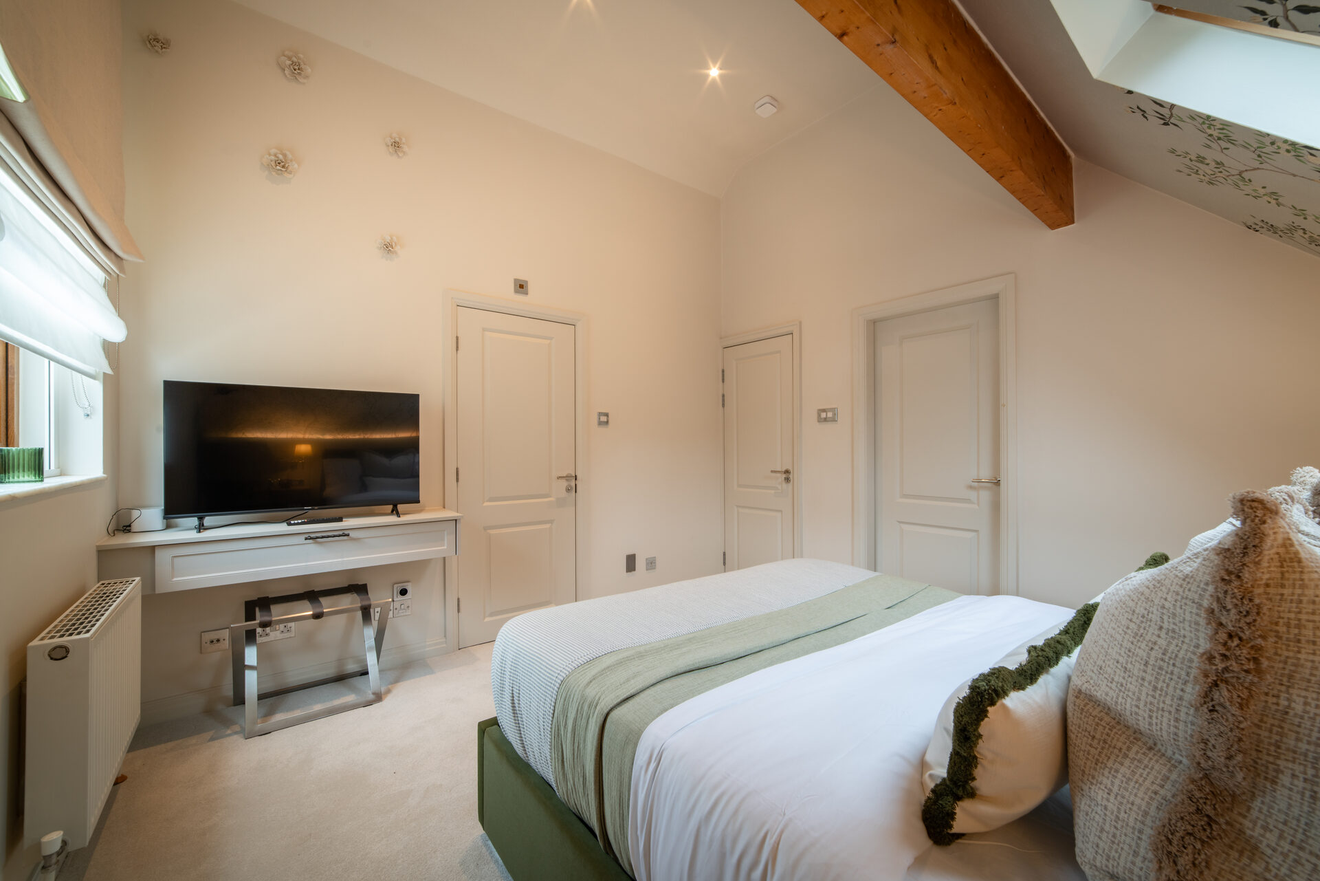 Woodland Room with exposed beam, green bedding and floral wallpaper accents