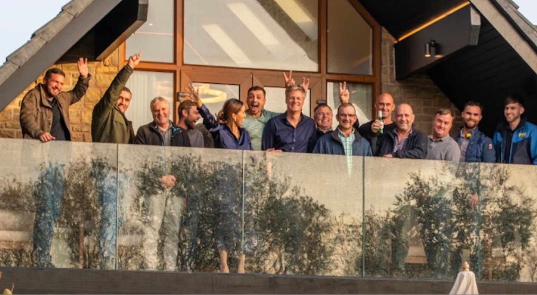 The Warren House build team celebrating on the balcony they rebuilt
